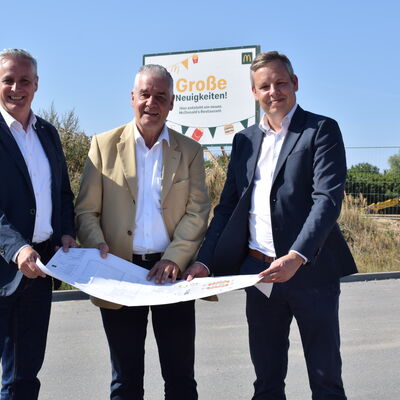 Franchisee Thomas Brand (von links), Sch&ouml;nkirchens B&uuml;rgermeister Gerd Radisch und Christian Dust (Immobilien Mc Donald's) beim Blick auf die Planzeichnung. 